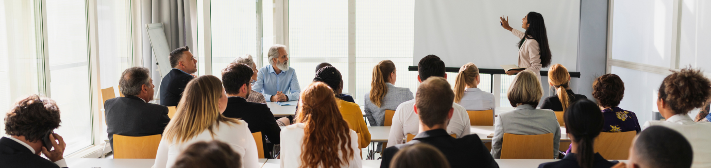 A woman giving a presentation in a room full of people