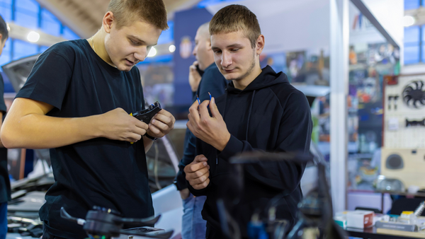 Two male high school students working in a car shop.