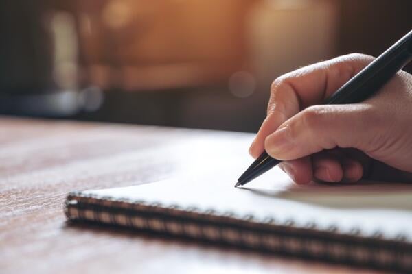 A person writing with a pen