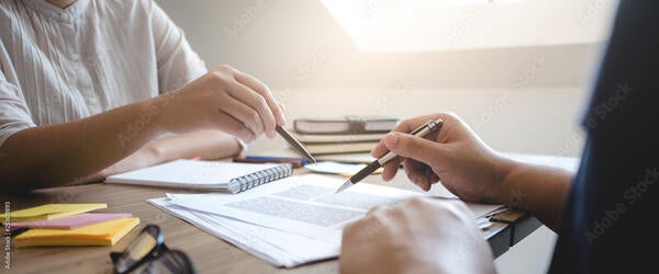 Two people working over a piece of paper