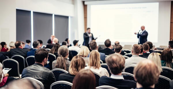People in a presentation room listening to two speakers