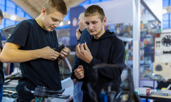 Two male students working in a car shop.