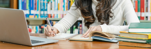 Student researching with notebooks and a laptop